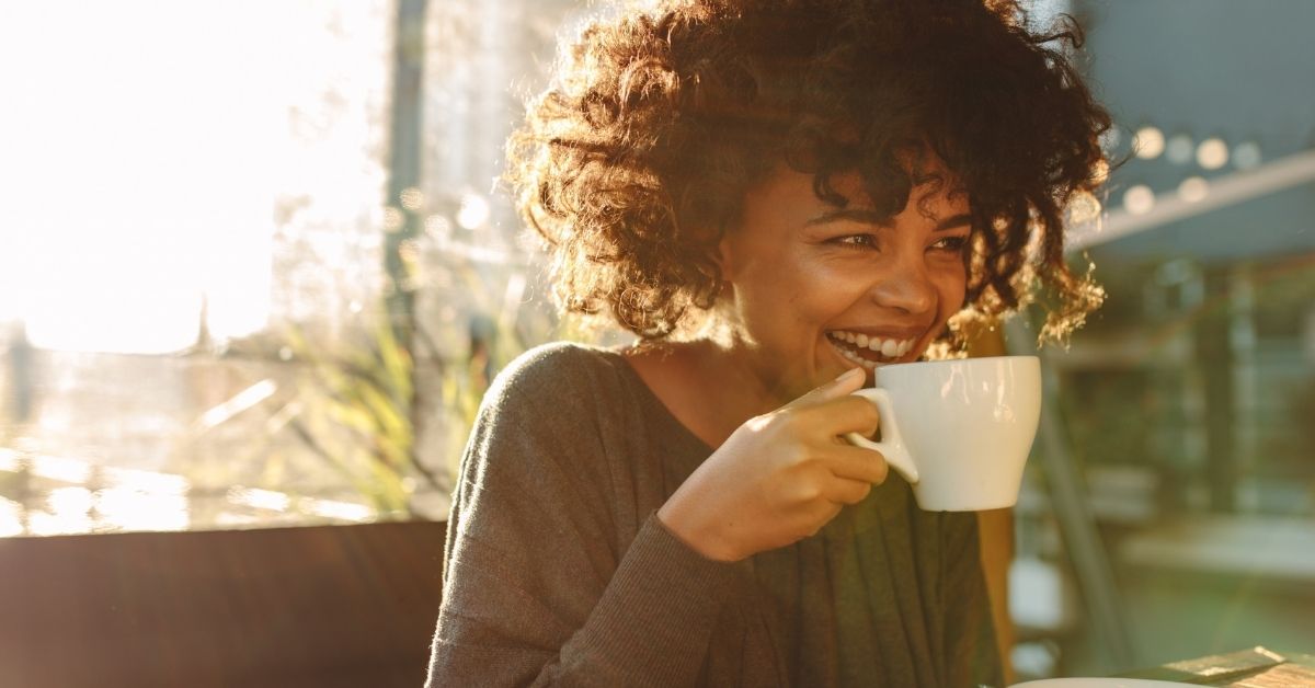 woman with mug inside smiling